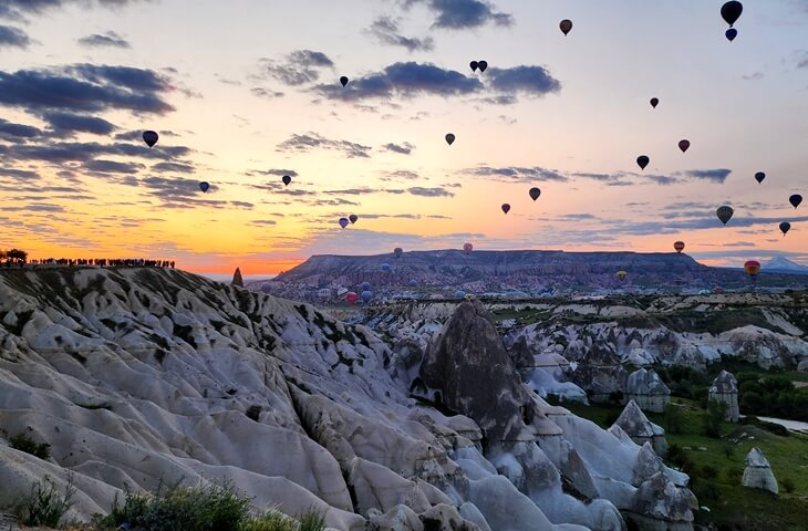 Kapadokya Aşk Vadisi gün doğumu manzarası, peri bacaları ve sıcak hava balonlarıyla